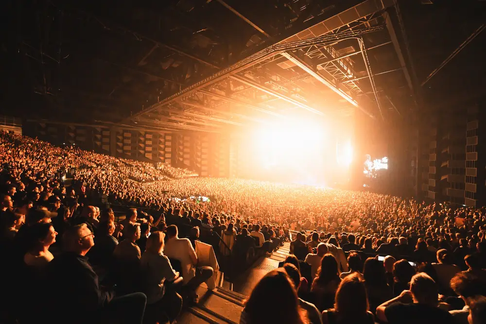 Grande salle de concert comble devant une scène baignée de lumière