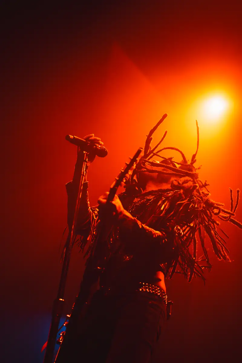 Lenny Kravitz chantant, dreadlocks en contre-jour rouge