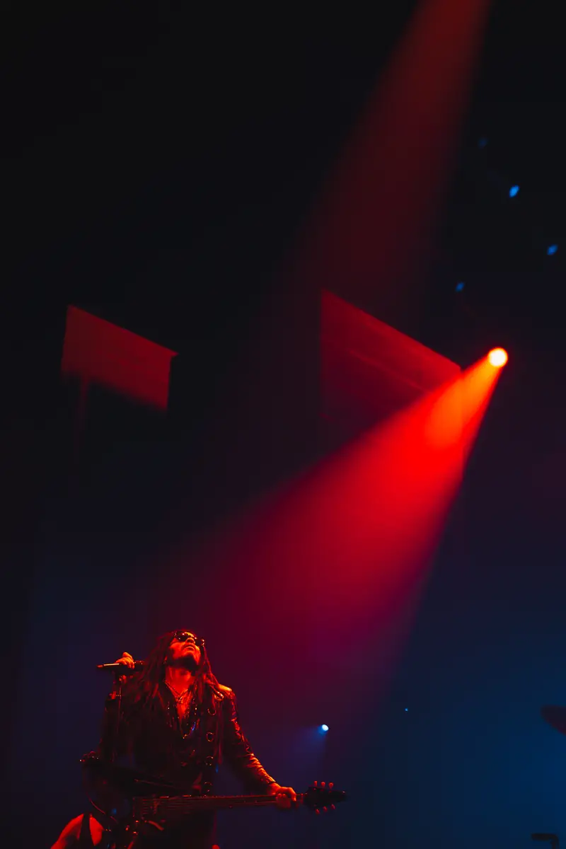 Lenny Kravitz à la guitare sous un projecteur rouge