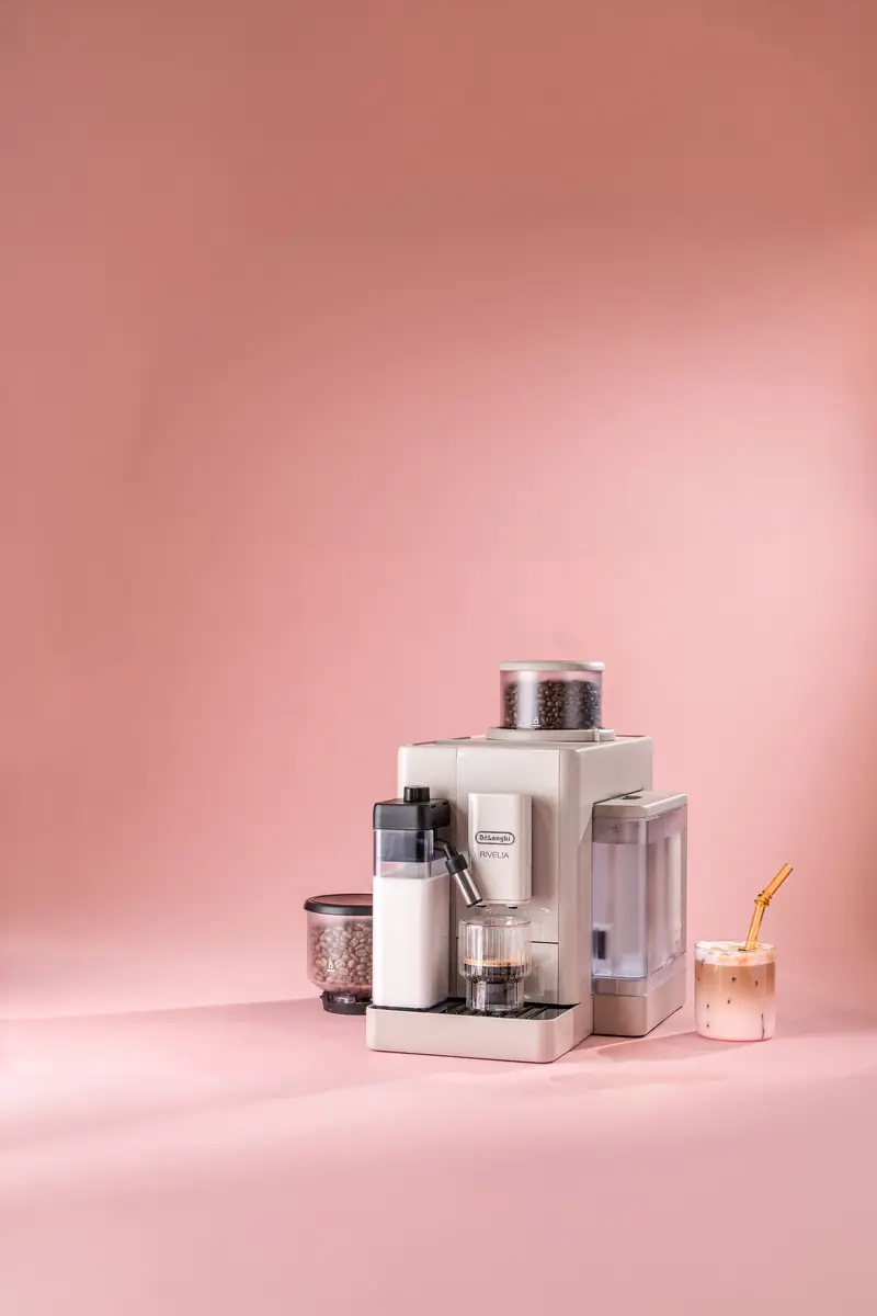 Machine à café avec carafe à lait sur fond rose