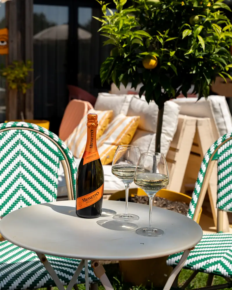 Mionetto Prosecco servi en terrasse à l'ombre d'un oranger